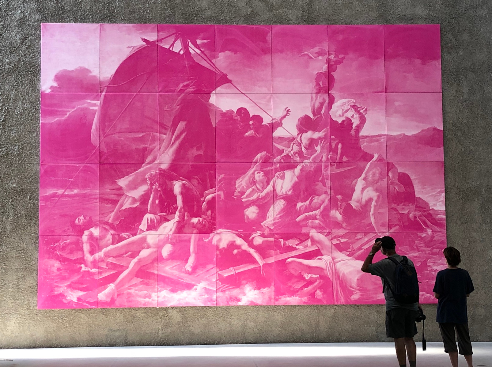 Large collection of canvases stiched together to form a pink version of a classic painting. Two people stand in front of it, admiring it.